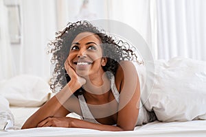 Happy black woman in bed thinking