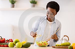Happy Black Woman Cooking Healthy Vegetable Salad Standing In Kitchen
