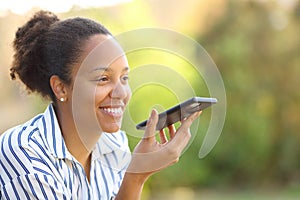 Happy black woman dictating message on cell phone