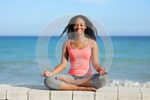 Happy black woman doing yoga on the beach