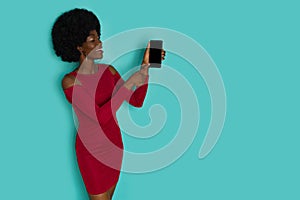 Happy Black Woman In Elegant Dress Is Holding Telephone And Pointing At It