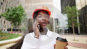 Happy black woman in helmet standing with coffee cup in daylight