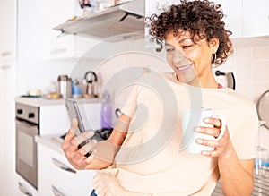 Happy black woman holding mobile phone in the kitchen at home