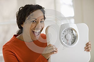 Happy black woman holding scale photo