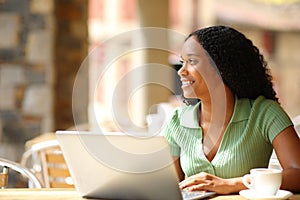 Happy black woman with laptop dreaming
