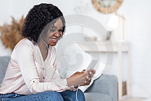 Happy Black Woman Listening Music On Smartphone At Home, Using Earphones