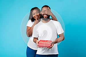 Happy black woman making surprise for her boyfriend giving box