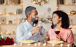 Happy black woman and man drinking wine and laughing