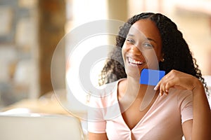 Happy black woman showing credit card in a terrace