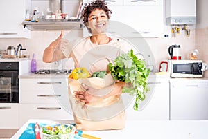 Happy black woman showing supermarket grocery paper bag