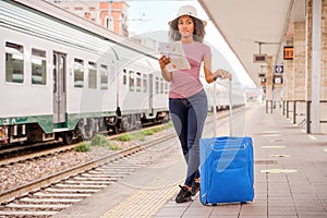 Happy black woman tourist waiting for the train in station