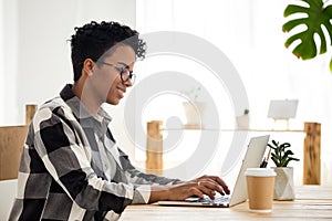 Happy black woman work at laptop having morning coffee