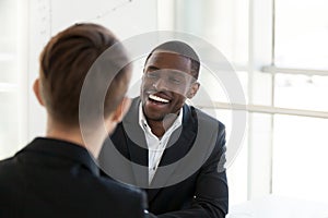 Happy black worker smiling having talk with colleague