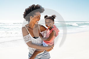 Happy black young mother carrying daughter at beach