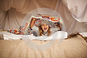 Happy, blanket fort and portrait of child relaxing and playing hide and seek with quilt at home. Excited, smile and face