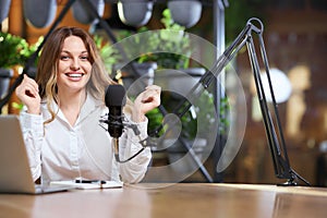 Happy blogger woman giving interview into microphone.