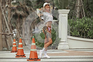 Happy blond girl riding her board on an road with hurdle, skateboarding.