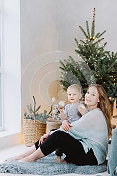 Happy blond hadsome boy and pretty woman playing under Christmas tree