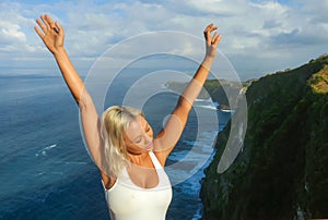 Happy blond tourist woman feeling free on the stunning view of beautiful sea cliff beach at viewpoint enjoying exotic Summer