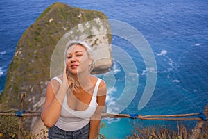 Happy blond tourist woman feeling free on the stunning view of beautiful sea cliff beach at viewpoint enjoying exotic Summer