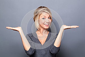 Happy blond woman displaying something equal on empty hands