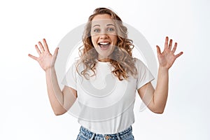 Happy blond woman shouting with joy, raising hands up and looking amazed, celebrating win and success, standing over