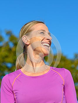 Happy blond woman standing outdoors laughing