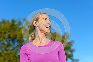 Happy blond woman standing outdoors laughing