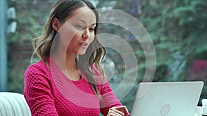 Happy blond woman using laptop having video conference in cafe