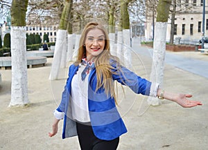 Happy blond young woman in the park with enigmatic smiling