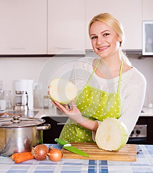 Happy blonde in apron holding cabbage