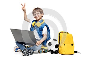Happy blonde boy sitting on yellow skateboard and holding notebook on white background. Back to School.