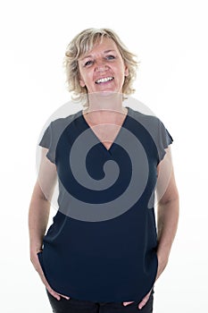 Happy blonde caucasian senior woman smiling and looking beautiful isolated on white background with hands in pockets of jeans