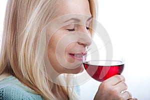 Happy blonde drinking red wine with eyes closed.