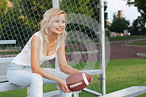 Feliz rubio Americano fútbol americano. feliz hermoso mujer joven sobre el bancos. afuera. ventilador de fútbol americano 