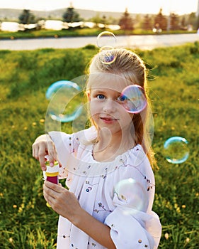 Happy blonde girl blowing soap bubbles