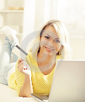 Happy blonde girl with credit card and notebook. Online shopping