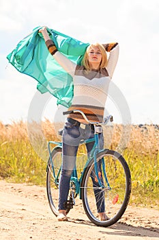 Happy blonde girl at cycling on dirt road