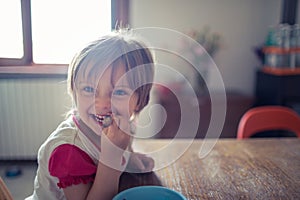 Happy blonde girl daughter with blue eyes smiling while playing on the living room wooden floor. Happy relaxed family