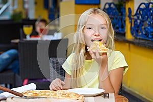 Happy blonde girl indoors eating pizza smiling