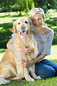Happy blonde hugging her dog in the park