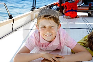 Happy blonde kid boy enjoying sailing boat trip. Family vacations on ocean or sea on sunny day. Healthy beautiful school