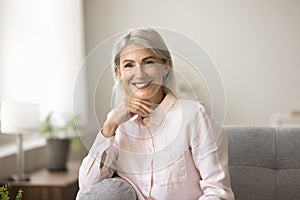 Happy blonde mature woman posing at home, looking at camera