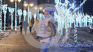 Happy blonde with packages walks at lights night city at winter