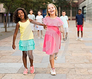 Happy blonde preteen girl walking with african american girl playmate