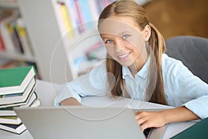 Happy blonde schoolgirl studying at a public library