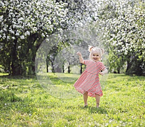 Happy blonde toddler girl having fun dancing in the park