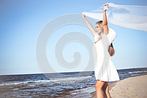 Happy blonde woman is catching clouds and wind with her arms on the ocean beach