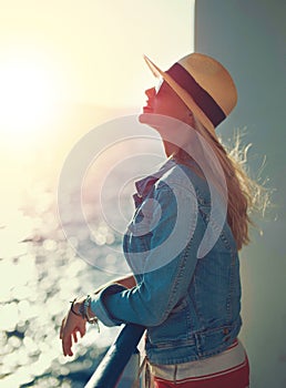 Happy blonde woman in hat enjoying the sunshine at sea