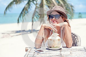 Happy blonde woman in hat and sunglasses on the tropical beach s